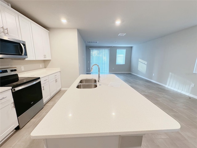 kitchen featuring white cabinetry, sink, stainless steel appliances, and an island with sink