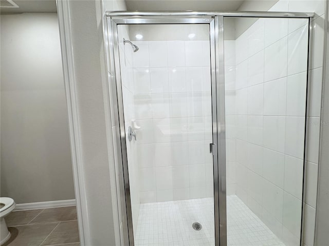 bathroom featuring tile patterned flooring, toilet, and walk in shower