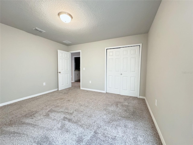 unfurnished bedroom featuring a closet, carpet, and a textured ceiling