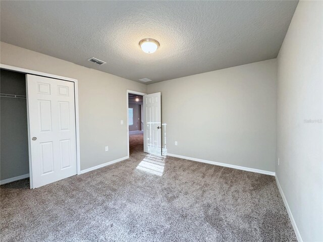 unfurnished bedroom with carpet flooring, a textured ceiling, and a closet