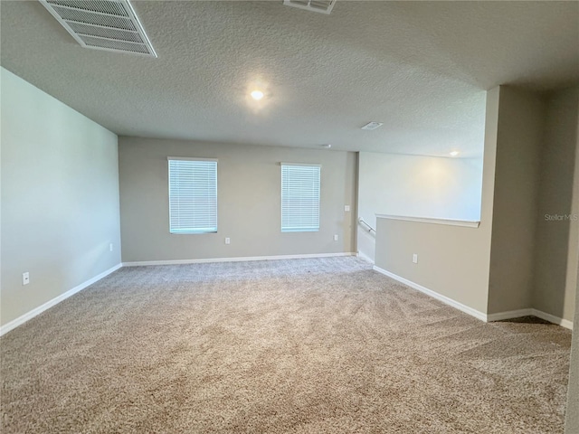 carpeted empty room featuring a textured ceiling