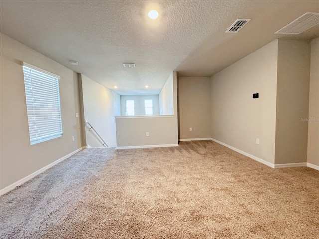 carpeted spare room with a textured ceiling