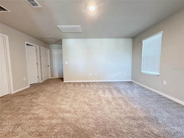 empty room featuring light colored carpet and a textured ceiling