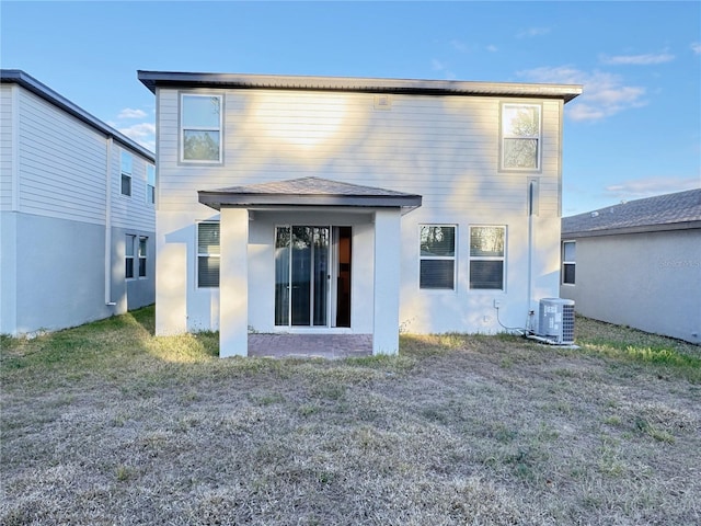 rear view of property featuring central AC unit and a lawn