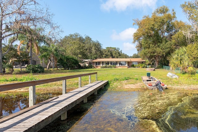 view of dock with a water view and a yard