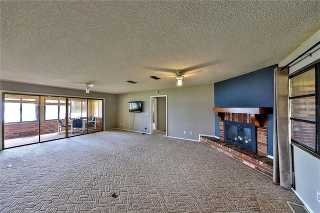 unfurnished living room featuring ceiling fan, a fireplace, carpet flooring, and a textured ceiling