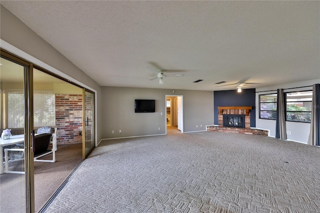 unfurnished living room with ceiling fan, a fireplace, carpet, and a textured ceiling