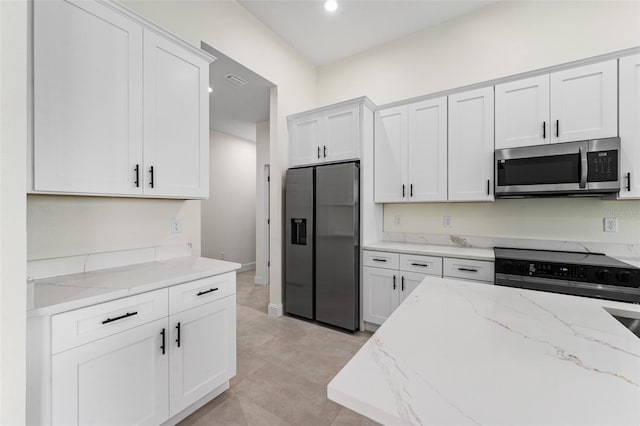 kitchen with light stone counters, appliances with stainless steel finishes, and white cabinets