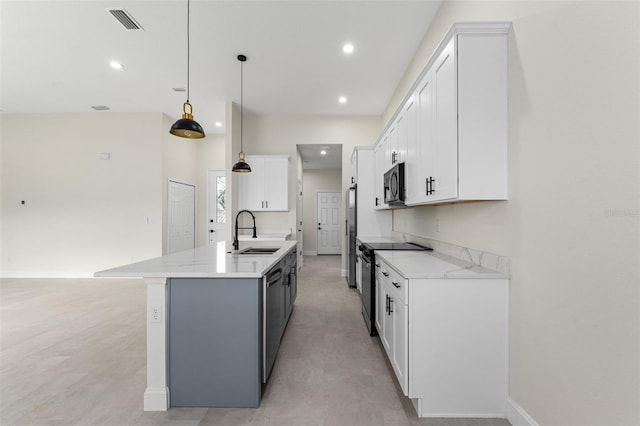 kitchen featuring appliances with stainless steel finishes, pendant lighting, sink, white cabinets, and a center island with sink