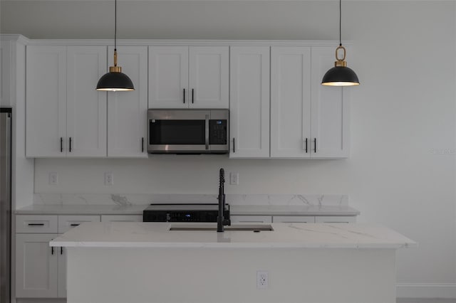 kitchen with decorative light fixtures, light stone countertops, sink, and white cabinets