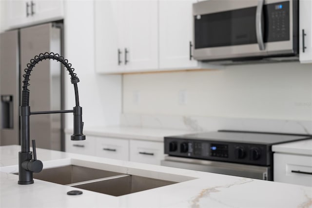 room details featuring white cabinetry, light stone countertops, and stainless steel appliances