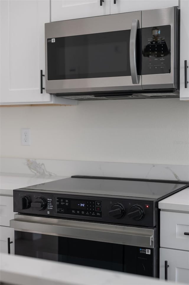 kitchen with white cabinetry, appliances with stainless steel finishes, and light stone countertops