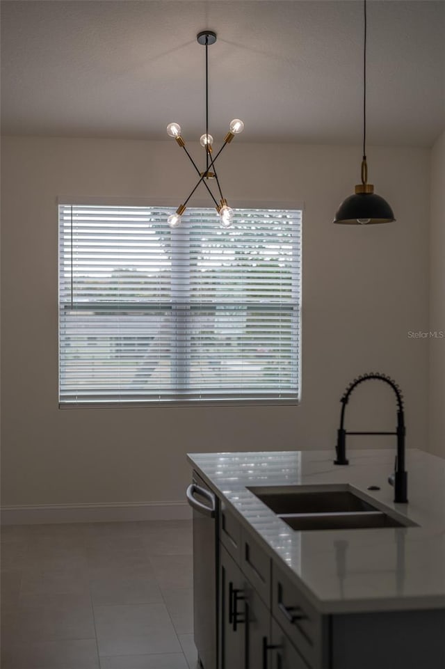 kitchen featuring dishwasher, sink, hanging light fixtures, light tile patterned floors, and light stone counters