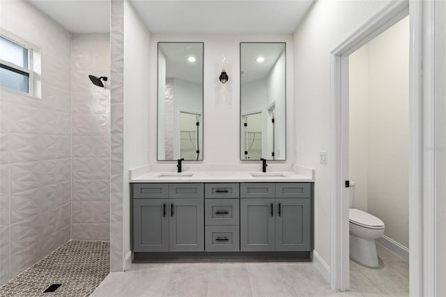 bathroom featuring vanity, toilet, and a tile shower