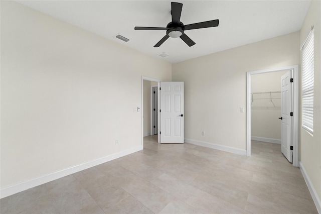 unfurnished bedroom featuring ceiling fan, a walk in closet, and a closet