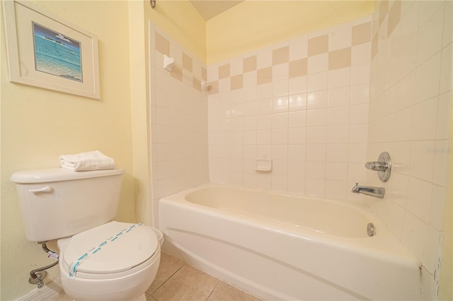 bathroom with tile patterned flooring, tiled shower / bath, and toilet