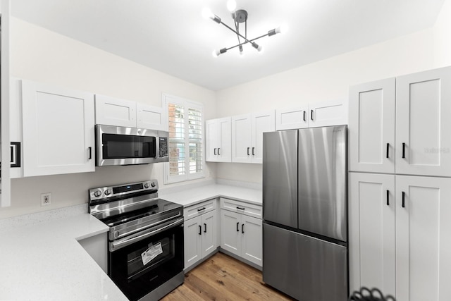 3013 Bonfire Beach Dr Unit 101, Kissimmee, FL 34746 - kitchen with stainless steel appliances, white cabinetry, light wood-type flooring, a chandelier, and light stone countertops