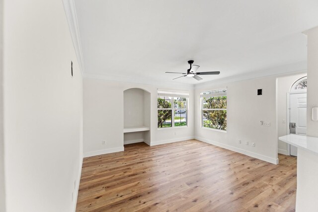 3013 Bonfire Beach Dr Unit 101, Kissimmee, FL 34746 - unfurnished living room featuring a ceiling fan, crown molding, light wood-style flooring, and baseboards