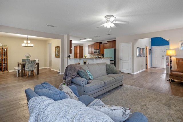 living room with ceiling fan with notable chandelier and dark hardwood / wood-style floors