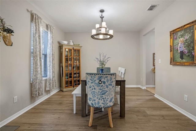 dining area with hardwood / wood-style flooring and a notable chandelier