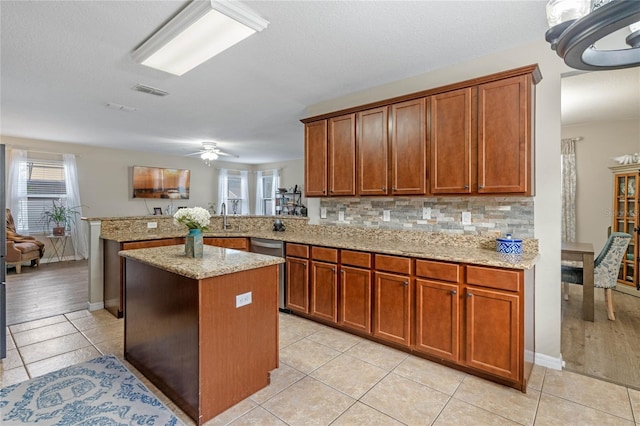 kitchen with sink, light tile patterned floors, kitchen peninsula, a kitchen island, and backsplash