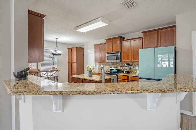 kitchen featuring tasteful backsplash, stainless steel appliances, kitchen peninsula, and a kitchen bar