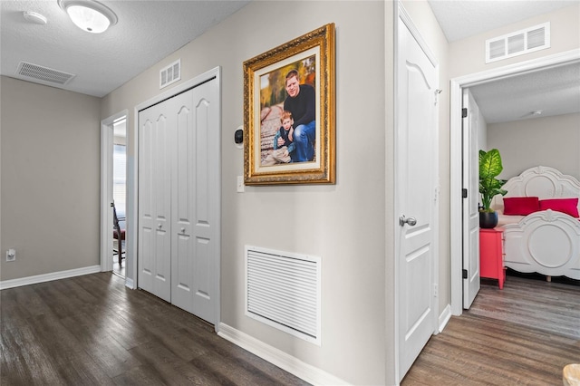 corridor featuring dark wood-type flooring and a textured ceiling