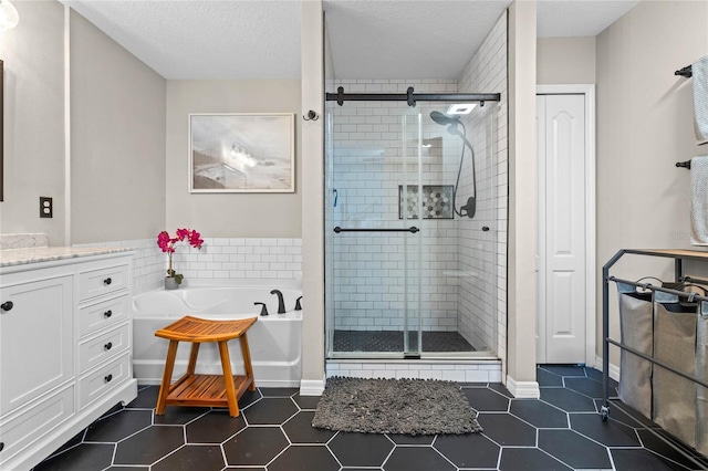 bathroom featuring tile patterned flooring, vanity, a textured ceiling, and plus walk in shower