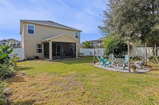 back of house with a lawn, a sunroom, and an outdoor fire pit