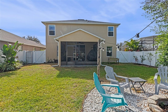 back of property with a sunroom, a lawn, and a fire pit