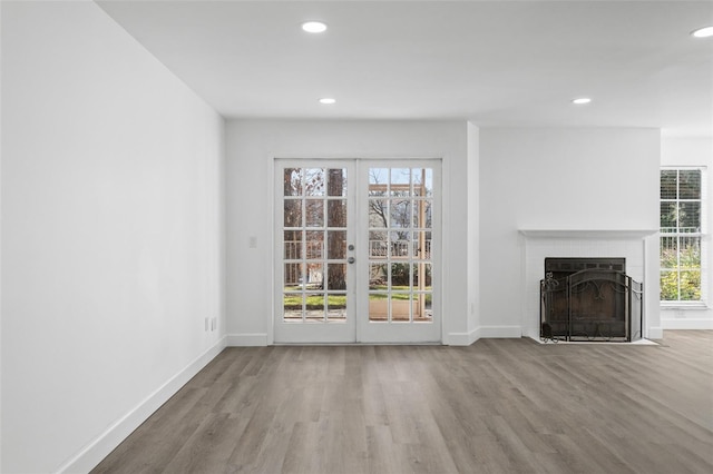 unfurnished living room featuring hardwood / wood-style flooring, a fireplace, and french doors