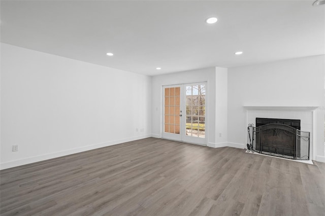 unfurnished living room with hardwood / wood-style flooring, a fireplace, and french doors