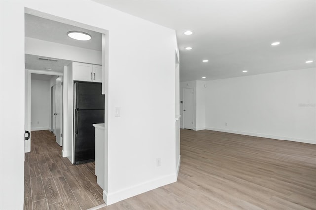 interior space with black refrigerator, white cabinets, and light wood-type flooring