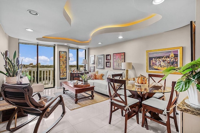 interior space with light tile patterned flooring, a wall of windows, and a tray ceiling