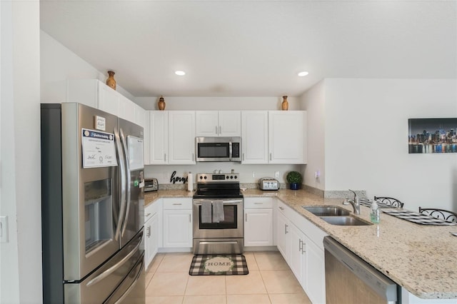 kitchen with sink, appliances with stainless steel finishes, white cabinetry, light stone countertops, and light tile patterned flooring