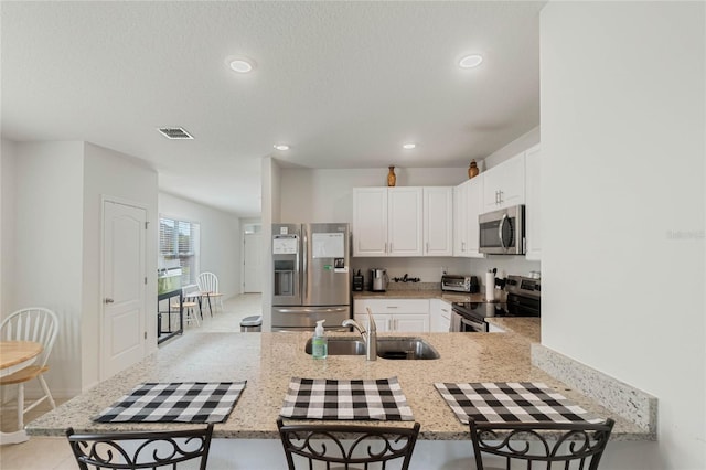 kitchen with white cabinetry, stainless steel appliances, kitchen peninsula, and sink