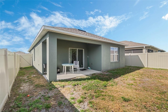 back of property with a yard and a patio