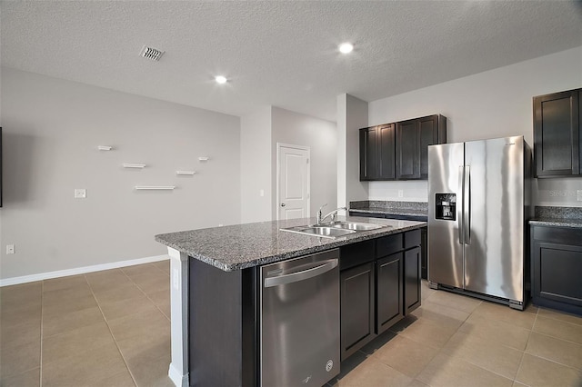 kitchen with stainless steel appliances, light tile patterned flooring, a kitchen island with sink, and sink