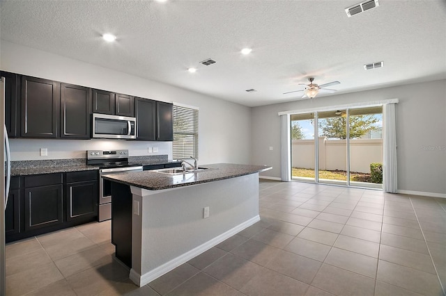 kitchen with sink, ceiling fan, stainless steel appliances, an island with sink, and light tile patterned flooring