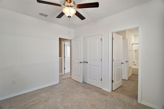 unfurnished bedroom with connected bathroom, light colored carpet, a closet, and ceiling fan