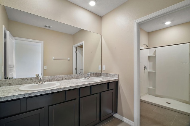 bathroom with tile patterned flooring, vanity, and a shower