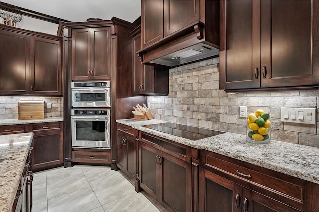 kitchen featuring premium range hood, tasteful backsplash, light stone counters, black electric cooktop, and double oven