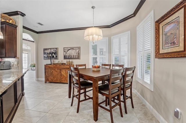 tiled dining space with ornamental molding and an inviting chandelier