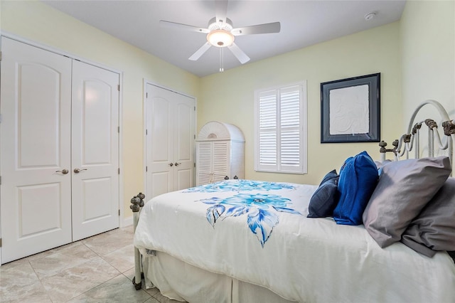 bedroom with ceiling fan, light tile patterned floors, and multiple closets