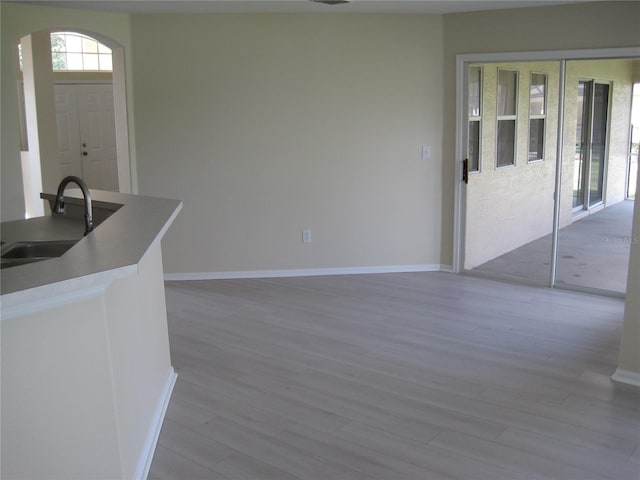 interior space featuring arched walkways, wood finished floors, a sink, and baseboards