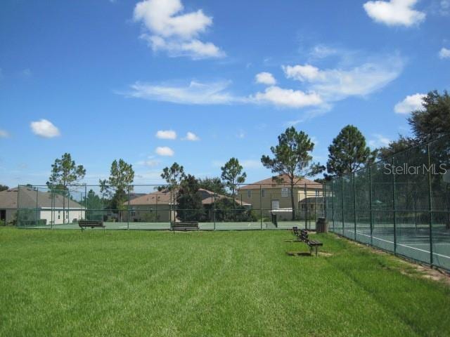 exterior space with a tennis court and fence