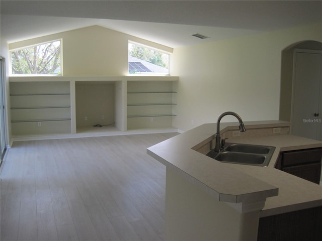 kitchen featuring lofted ceiling, a sink, visible vents, light wood-style floors, and light countertops