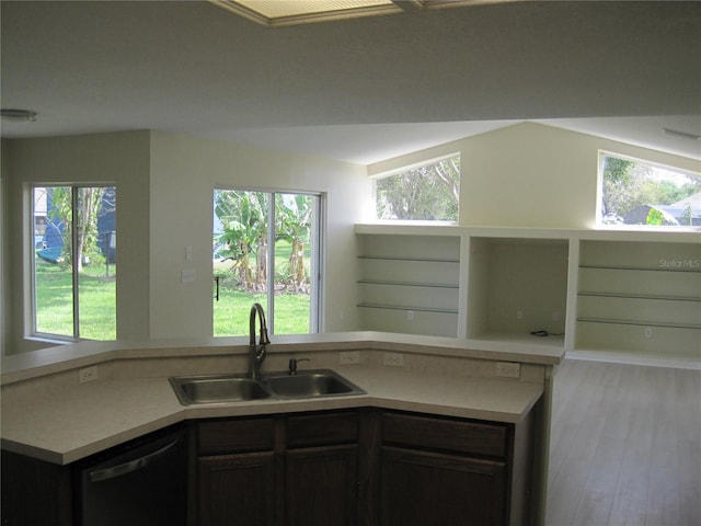 kitchen featuring a sink, open floor plan, light countertops, light wood-type flooring, and dishwasher