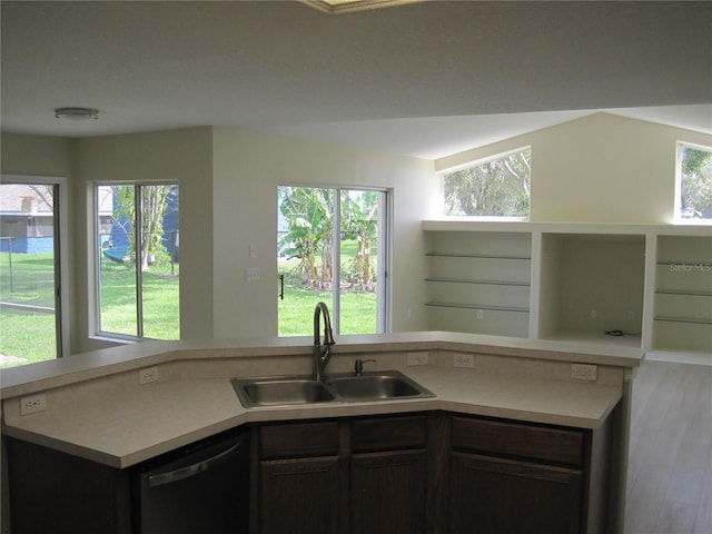 kitchen with dishwashing machine, open floor plan, wood finished floors, light countertops, and a sink