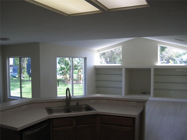 kitchen featuring dishwasher, light countertops, open floor plan, and a sink